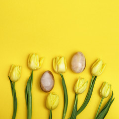 Easter composition with natural flower of tulips and decorative eggs from gemstone onyx. Spring Easter holiday pattern for greeting card with copy space. Flat lay.