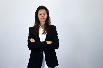 Portrait of pretty caucasian bussiness woman stands with arms folded, isolated on gray background studio shot, white shirt and black jacket, dark air. Place for your text in copy space.