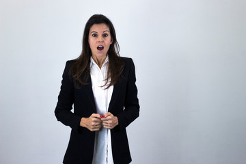 Portrait of caucasian bussiness woman model with stunned expression, keeps mouth opened, isolated on gray background studio shot, white shirt and black jacket. Place for your text in copy space.