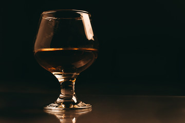glass of cognac on a dark background with a warm filter close up