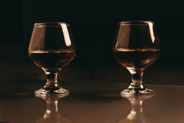 Two glasses with cognac on a dark background with a warm filter