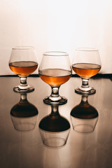 three glasses of cognac on a white background with a warm filter
