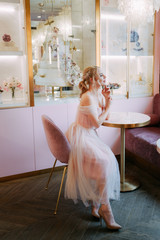 Spring portrait of a beautiful sensual sexy attractive young pretty romantic elegant blonde in a delicate puffy pink dress in a floral pink cafe, princess, morning bride, inspiration, nature