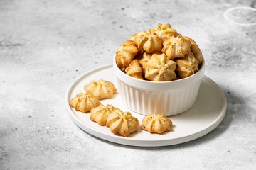 Lemon cookies with poppy seeds in a white ceramic bowl on the gray kitchen table. Shortbread. Space for text	