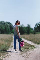 Obraz premium Outdoor portrait of middle aged beautiful happy smiling woman posing. Model with peonies. Life after forty. Freedom. Copy, empty space for text. 