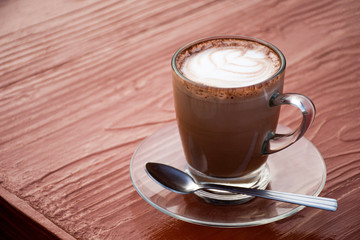 cup of coffee with cream on wooden background