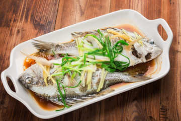 There is a plate of steamed sea bream on the table