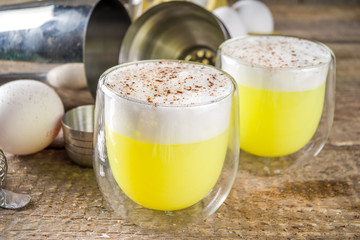 Autumn Homemade Bourbon Egg Flip Cocktail with spices, wooden background with ingredients