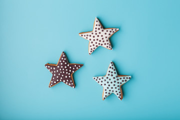 Close-up of three homemade glazed gingerbread cookies made in the form of stars on a blue background. Handmade cookies. Free space.