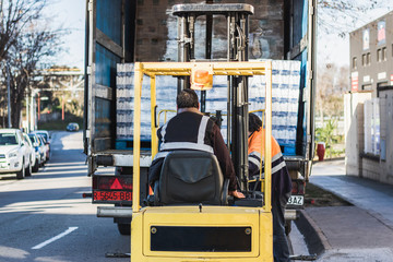 Man with forklift loading boxes and riding them in a truck