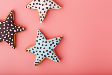 A close-up of three homemade glazed gingerbread cookies is made in the form of stars on a pink background. Handmade cookies.