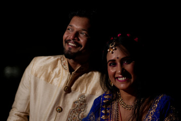 Young and beautiful Indian Gujarati couple in Indian traditional dress celebrating Diwali with diyas/lamps on the terrace in darkness on Diwali evening. Indian lifestyle and Diwali celebration