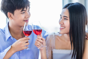 Valentine's day concept,Happy Asian Young sweet couple having romantic the Lunch with clinking toasting wine glasses at the restaurant background.