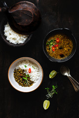 Delicious Split Black Lentils Curry /Urad dal served with aromatic rice, garnished with fenugreek sprouts on dark wooden background. Vegetarian Indian cuisine