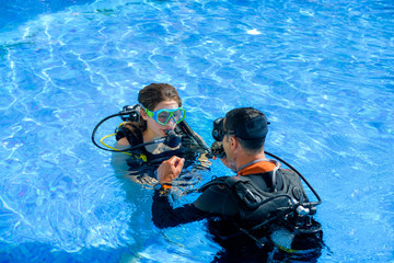 beautiful young woman taking a scuba diving lesson in swimming pool