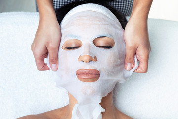 Cosmetologist making the vitamin C facial mask for rejuvenation to woman on the spa center.