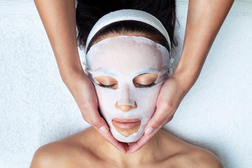 Cosmetologist making the vitamin C facial mask for rejuvenation to woman on the spa center.