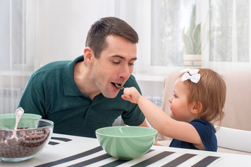 Shot of young father  taking care of a little daughter at home.