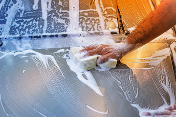 A man washes the hood of a car