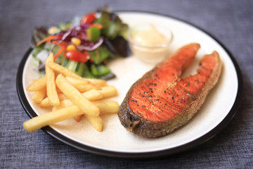 Fried salmon steak, chips and vegetables salad Selective focus only salmon. blur background