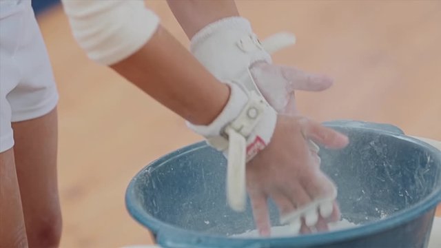 The gymnast carefully rubs his hands with talcum powder to increase grip. Close up. Gymnast before the performance.
