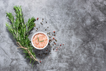 Bunch of fresh organic rosemary, Himalaya salt and peppercorn mix on dark stone background with copy space for your design. Template restaurant menu or culinary blog social media.