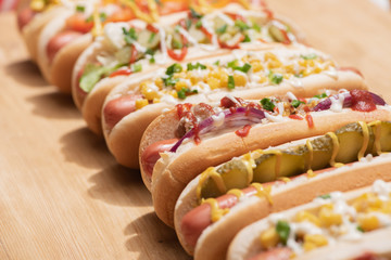 selective focus of fresh various delicious hot dogs with vegetables and sauces on wooden table
