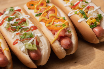 fresh various delicious hot dogs with vegetables and sauces on wooden table
