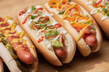 fresh various delicious hot dogs with vegetables and sauces on wooden table