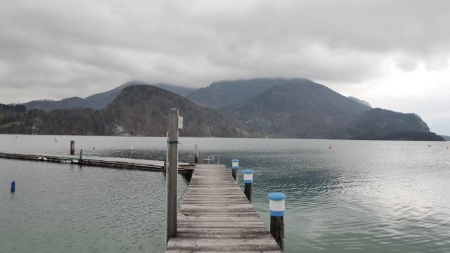 Pier on the lake with mountains and clouds