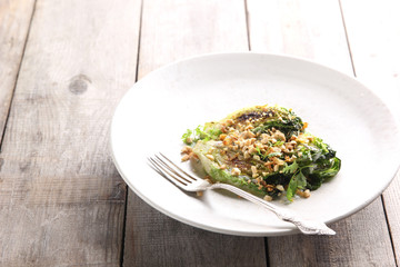 Diet food. Fried cabbage with nuts and sauce in a light plate on a wooden background. Background image, copy space
