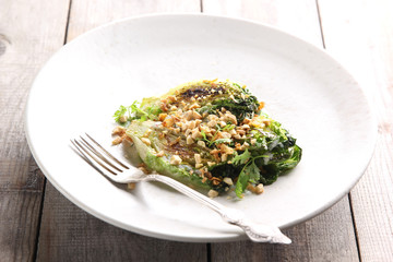 Diet food. Fried cabbage with nuts and sauce in a light plate on a wooden background. Background image, copy space