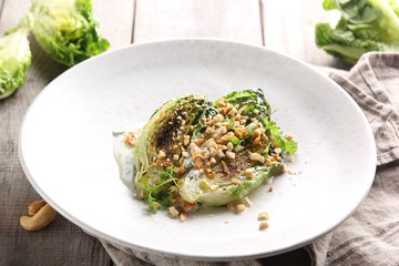 Diet food. Fried cabbage with nuts and sauce in a light plate on a wooden background. Background image, copy space