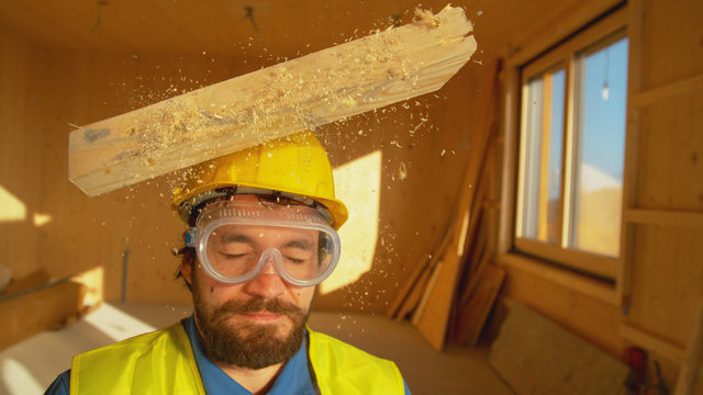 PORTRAIT, CLOSE UP: Wooden board falls on an unsuspecting builder's head.