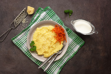 Mashed potatoes with parmesan and carrots on a dark background. Vegan or vegetarian lunch and dinner. Top view, flat lay.