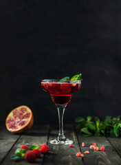red cocktail with champagne and pomegranates on rustic background