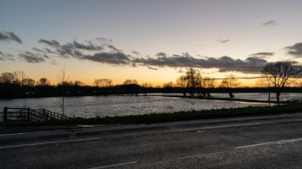 Fototapeta premium Floods in Thame town, Oxfordshire winter floded lands, sumset by the water, river overflow for new animal habitat