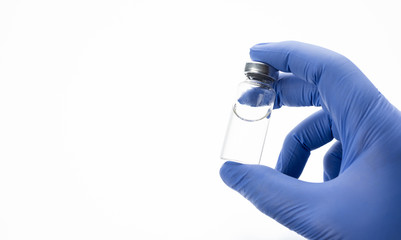 Glass medical bottle in a doctor's hand. A bottle with a transparent antibiotic or vaccine holds a palm in silicone gloves on a white background.