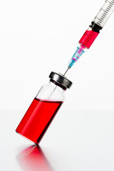 Medical ampoule with a syringe. Red medicine in a glass bottle. Antibiotic or vaccine against the...