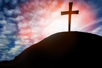 Silhouette cross on Calvary mountain sunset background. Easter concept