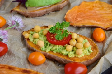 Sweet potato toast with avocado, tahini, chickpea, cherry tomatoes, hemp seed and radish sprouts on parchment paper