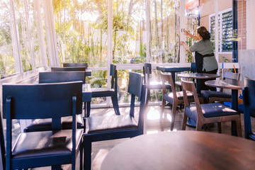 Back view of maid closes the glass window to turn on the air conditioner in the coffee shop.