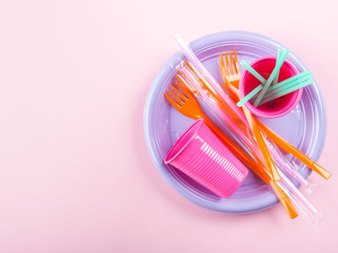 Disposable colorful plastic dishes, cutlery, straws and glasses. Creative Flat lay