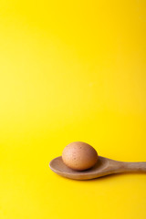 Easter egg on wooden spoon on yellow background