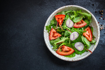 Fototapeta na wymiar healthy salad tomato, mix leaves, onions and other ingredients, vegan, keto or paleo menu concept. top food background. copy space
