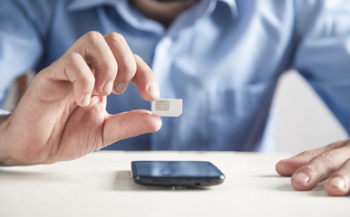 Man holding Sim Card. Smartphone on the desk