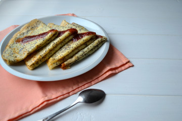 Traditional Russian and Ukrainian this pancakes with poppy seeds and strawberry jam on a white...