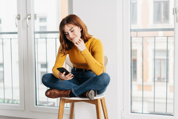 Woman with phone on a chair with crossed legs