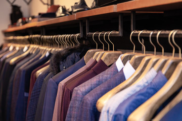 Fototapeta premium Closeup colorful male, female clothes in boutique hanging on hangers, clothing rack on metal stand. Concept opening luxury shop, shopping mall, store sale, retail fashion store, second hand outlet.