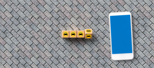 cubes with car symbol and text TAXI and a smartphone on stone background